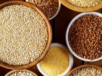 Bowls of millets, grains, and seeds on a wooden surface